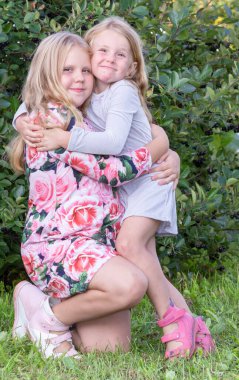 Küçük kız kardeşler güneşli, sıcak bir yaz gününde sokakta yürüyorlar..