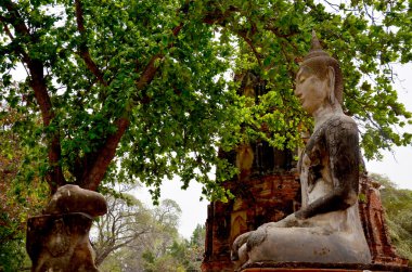 Kırık Buda heykeli ve eski bina
