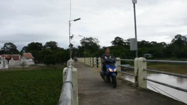 Tayland 'ın Uthai Thani Eyaleti' ndeki Uthaithani şehrine 20 Ekim 2020 'de bisikletle gezen ve küçük bir köprüde motosiklet süren Taylandlı insanların hayatı.