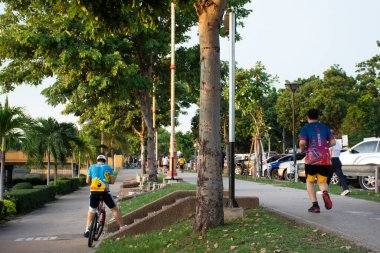 15 Eylül 2020 'de Tayland' ın Udon Thani kentindeki Nong Prajak halk bahçesi parkında gölet kenarında bisiklet sürerek yürüyüş yapan Asyalı Taylandlı ve yabancı gezginler.