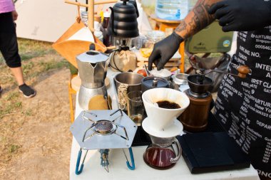 Thai men barista people use drip coffee maker or dripper made hot and iced coffee for sale beside irrigation canal at Bangbuathong city rural countryside on March 13, 2021 in Nonthaburi, Thailand