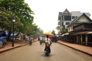 Laos 'ta 7 Nisan 2016' da Luang Prabang, Laos 'ta sokak trafiğinde bisiklete binen ve kaldırımda yürüyen Laoslu yabancılar antik Luangprabang şehrini ziyaret etti.