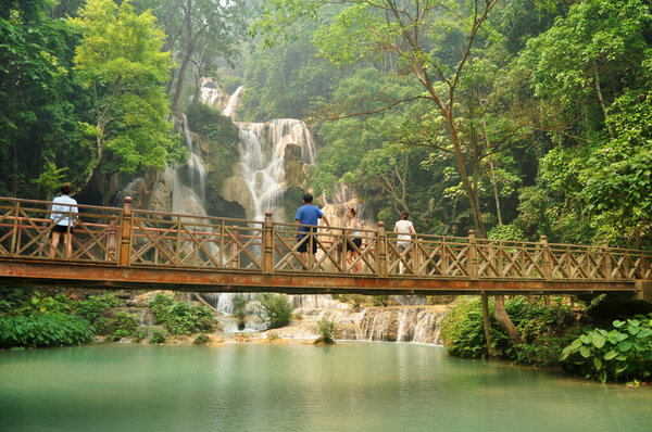Laotian people foreign travelers travel visit on wooden bridge for looking and take photo at viewpoint of Tat Kuang Si Falls Waterfalls at Luangprabang Lao city on April 8, 2016 in Luang Prabang, Laos