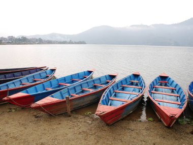 Nepal 'de Phewa Tal veya Fewa Freshwater Gölü' nde yüzen ahşap kano insanları, Nepalliler ve yabancı gezginler Nepal 'deki Gandaki Pradesh' in Pokhara kasabasını ziyaret ediyor.