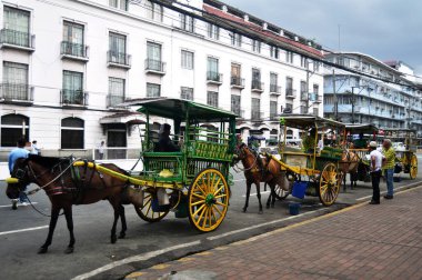 Filipinliler at arabalarına biniyor ve Filipinliler ve yabancı gezginler 17 Nisan 2015 tarihinde Manila, Filipinler 'de Maynila' da Intramuros Meydanı 'nda servis turu yapıyorlar.