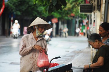 Vietnam 'da 7 Temmuz 2012' de Hanoi, Vietnam 'da, Hoan Kiem şehrinde, Hang Buom yürüyüş sokağındaki Vietnamlılara ve yabancı yolculara yol satışı yapan bisiklet arabası kullanan Vietnamlı kadınlar.