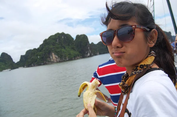 Traveler thai women people eat banana bad tasty between travel visit on cruise tour trip more 2,000 islets limestone and in Halong or Ha Long Bay UNESCO World Natural Heritage Site in Hanoi, Vietnam