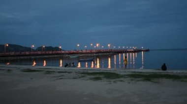 Taylandlılar ve yabancı gezginler için Saphan Saranwith kırmızı köprüsü ile deniz manzarasını izleyin. 6 Eylül 2021 'de Tayland, Tayland' da Prachuap Khiri Khan 'da gece gezintisi ve dinlenmesi.