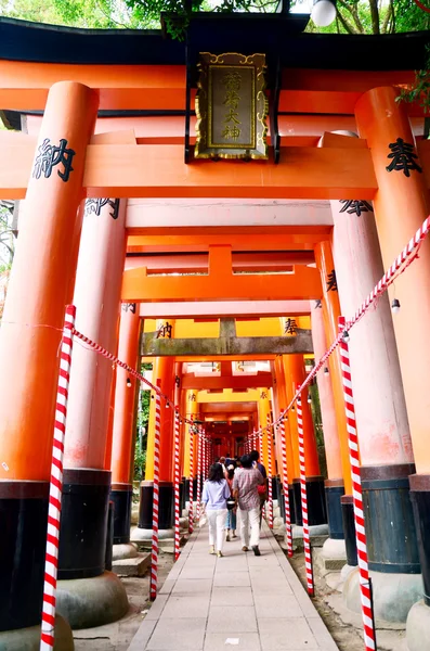 Människor reser och stigen inne genom en tunnel av torii — Stockfoto