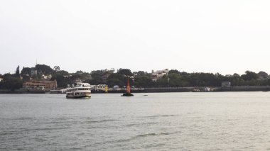 17 Ekim 2025 tarihinde Çin 'in Fujian şehrinde Xiamen şehrinde seyahat eden Çinli insanlar için feribot ve şehir merkezi Gulangyu Adası veya Pianos Kasabası manzaralı deniz manzaralı Lujiang nehrine bakın.