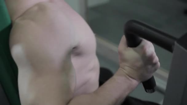 Anak muda berlatih di mesin pers dada di gym. Dia membuat upaya besar untuk melanjutkan latihan — Stok Video