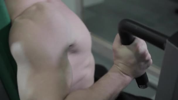 Jonge Man opleiding op Chest Press Machine in de sportschool. Hij maakt grote inspanningen voort te zetten van de uitoefening — Stockvideo