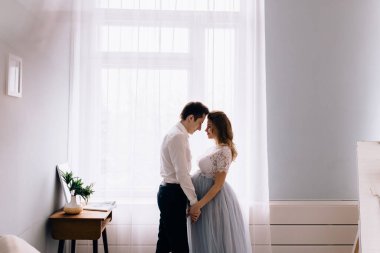 Windo 'nun önünde kocası olan hamile bir kadın.