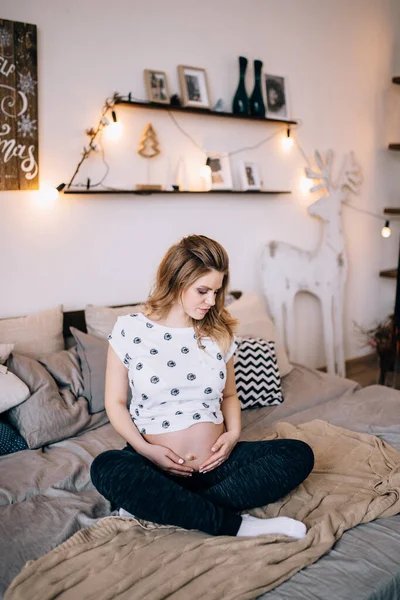 人和期待值概念 幸福微笑的孕妇围坐在床上 在客厅里摸她的肚子 — 图库照片
