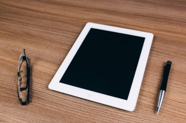Tablet, gözlük ve kalem masanın üzerinde.