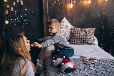 Bebek, anne kurabiyelerini oturma odasında besliyor. 