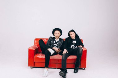 Kanepede ya da koltukta oturan ve beyaz arka planda izole edilmiş kameraya bakan iki mutlu adam.. 