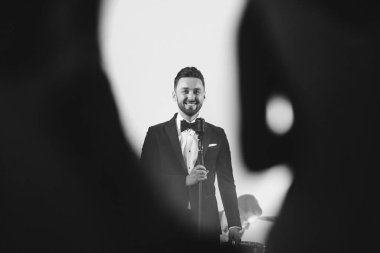 Takım elbiseli adam sahnede şarkı söylüyor.