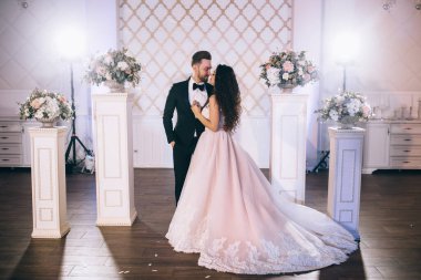 Çok güzel ve mutlu yeni evliler düğün törenlerinde güzel dekore edilmiş bir düğün kemerinin yanında dururlar.