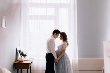 Pencerenin önünde kocası olan hamile bir kadın.