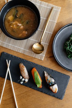 Masada bir yemek seti. Çorba, nigiri suşi, salata.