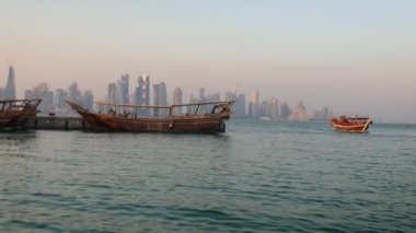 Doha Katar 'da Doha silueti öğleden sonra yakınlaşıyor ve çekimde Katar bayraklarıyla Arap Körfezi' nde Dhows 'u ve sahnenin tadını çıkaranları gösteriyor.