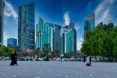 Doha Katar 'daki Sheraton Parkı' nın öğleden sonra çekimlerinde parkın keyfini çıkaranlar, Doha silueti ve arka planda bulutlar