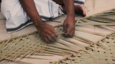 Arap bir adam geleneksel sanat ve el işi yapmak için palmiye yaprakları dokuyor. El yapımı el sanatları. İş yerinde ellerinizi kapatın..