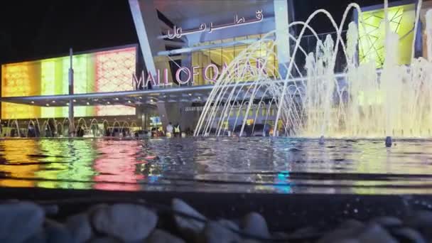 卡塔尔首都多哈的购物中心在夜间的放大和拍摄中显示了前景光明的喷泉和背景下的大门 人们和汽车都在移动 — 图库视频影像