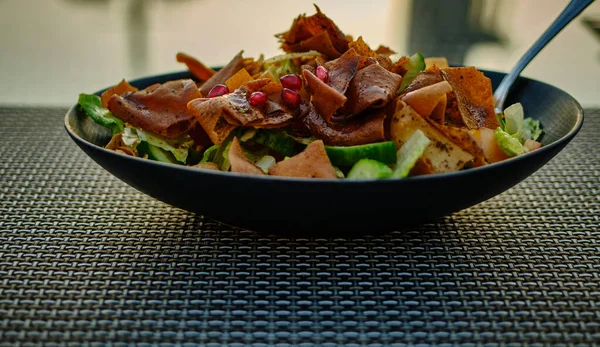 Fattoush (Lübnan salatası), arka planda bulanık siyah bir tabakta görüntüyü kapat. Sebze ve çıtır tost ekmeği ile yapılır, sosu güzelce emer.. 