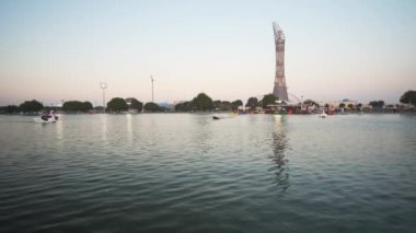 Doha Katar 'daki Aspire Parkı. Gün ışığı altında, arka planda Torch Doha Oteli' nin olduğu yüzgeçli teknelerdeki insanları gösteriyor.