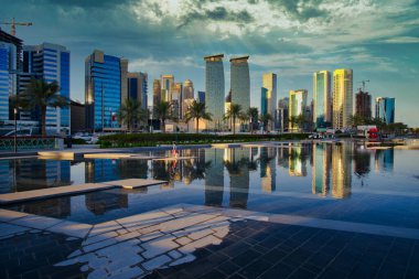 Batı körfezindeki Doha silueti öğleden sonra Sheraton Parkı 'ndan çekildi. Ön planda yapay göl, arka planda bulutlar.