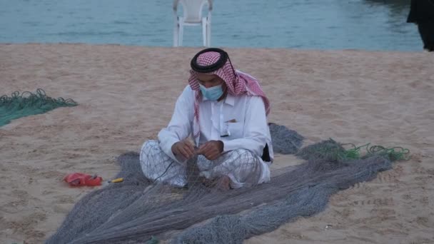 在卡塔尔多哈举行的卡塔拉第十届传统三角帆船节 一名阿拉伯手工艺者坐在海滩上 并在下午把鱼网放大 — 图库视频影像