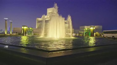 Doha, Katar - 2 Şubat 2026: İslami Sanat Doha Müzesi, Katar dış gece çekimi ön plandaki çeşmeyi ve arka plandaki müzeye arabalarla ve yürüyen insanlarla birlikte ana girişi gösteriyor