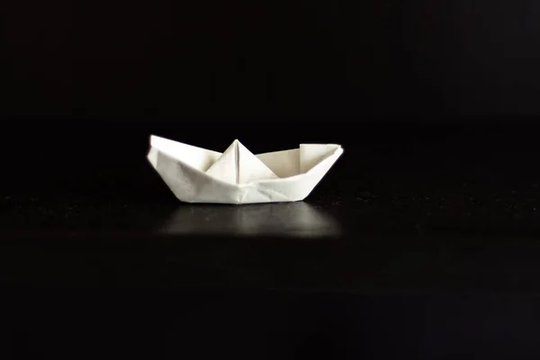 Origami white paper boat in black background