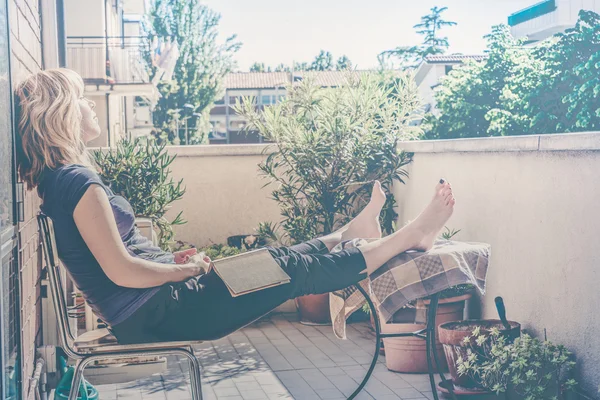 Lazy woman with book sitting on balcony Stock Image