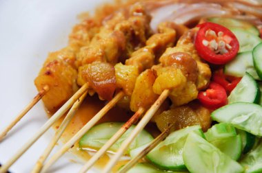 Kırmızı biberli domuz eti ve beyaz tabakta salatalık.