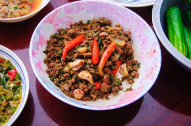 Tabakta yemek, biber sarımsak ve ahşap masada salatalık.