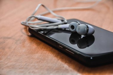 Beyaz dijital kulaklıklar ahşap bir masadaki akıllı telefonlarda.