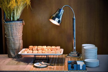 Masadaki ekmek ve tabağı aydınlatan bir lamba.