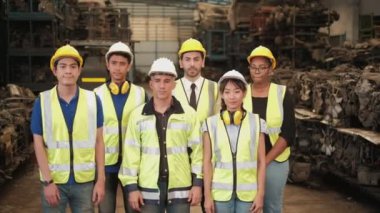 Üniformalı ve kasklı mühendislerden oluşan çeşitli etnik gruplar ayakta, çapraz silahlanmış ve mutlu bir şekilde gülümsüyor. Tüm iş arkadaşları yedek parça depolama fabrikasında profesyonel takım çalışmasıdır..