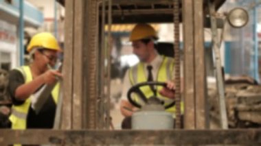 Bulanık odaklı VDO: Kafkas erkek forklift sürücüsü, endüstriyel fabrikaların deposundaki yedek parça stoklarını kontrol etmek için siyah bir kadın mühendisi bekliyor. Ve kız geldiğinde, adam geri geri gitti..