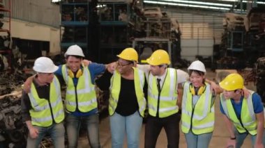 Fabrikanın çeşitli etnik kökenlerine mensup işçiler ve mühendisler makine yedek parça depolarındaki siparişlerin başarısını kutlamak için kucaklaştılar ve sallandılar. Bazıları dans etmeye ve şarkı söylemeye geldi..