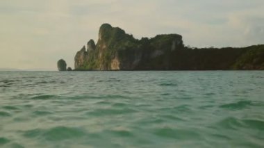 Pan tekniği VDO: Zümrüt deniz dalgaları ve Tayland kıyısındaki yeşil kayalık uçurumlardan oluşan güzel bir manzara. Doğal olarak, turistler yaz tatilinde dinlenmeyi severler..