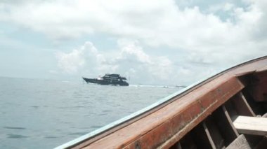Tahta tekneden bakıldığında, Phi Phi Adası 'na turist taşımak için okyanus trafiğinin tıkandığı görülüyor. Hem feribot, hem yolcu sürat teknesi deniz taşımacılığı Andaman Denizi 'nde beyaz su sıçraması yaratır..