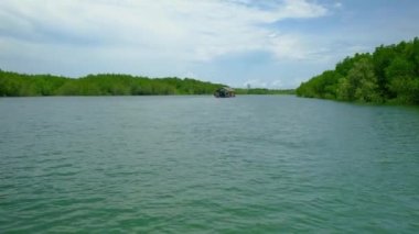 Tayland 'ın sarı nehir su yollarından birinde yemyeşil mangrovlar arasında geleneksel bambu raftingi ile ekosistemi gezmek. Kanalların ve ormanların tropikal ortamında bir açık hava macerasıdır..