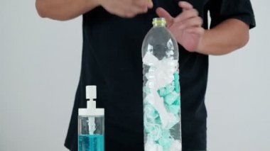 İnsan, kullanılmış maskeyi boş bir şişeye koyar ve ellerini hijyen için alkol jeliyle temizler. Böylece hastalık, koronavirüs enfeksiyonu (COVID-19) ve bakterilerin yayılmasını önler..