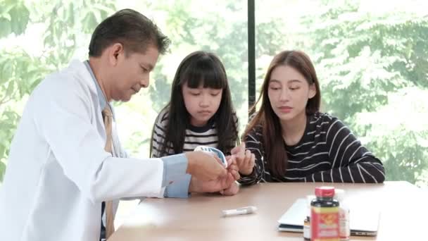 アジアの男性医師の健康相談 近くの子供たちと一緒に医療のための親の診療所の母親である女性の糖尿病をチェックする血糖テストケア — ストック動画