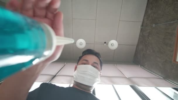 ロフトスタイルの天井の背景に撮影された低角度ビュー アルコールゲルドロップの顔マスクプレスボトルを持つ男と下に流れます 手洗いは病気を予防し コロナウイルスなどの細菌 Covid — ストック動画