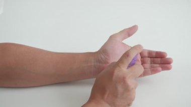 Beyaz arka planda yakın çekim: Yüz maskeli Asyalı erkek, alkol spreyiyle güvenlik için ellerini ve parmaklarını temizliyor, bakterileri, koronavirüsü (COVID-19) ve sağlıklı hijyen enfeksiyonunu önlüyor.